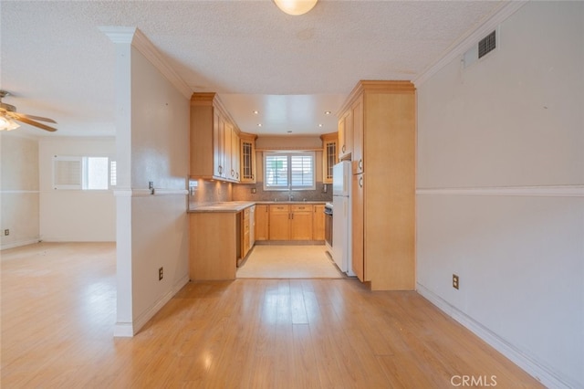 kitchen featuring freestanding refrigerator, visible vents, light wood-style floors, glass insert cabinets, and ceiling fan