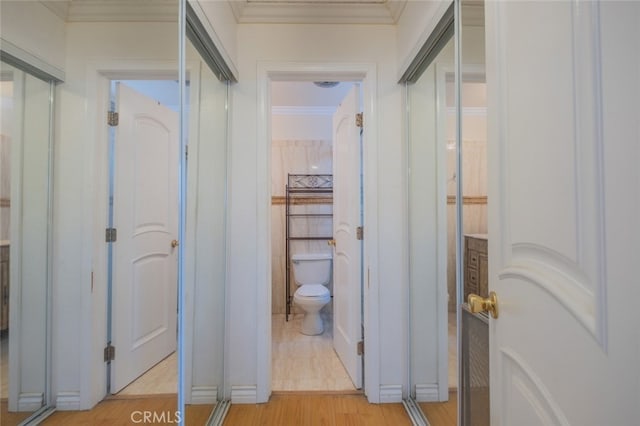 hallway featuring light wood finished floors and ornamental molding