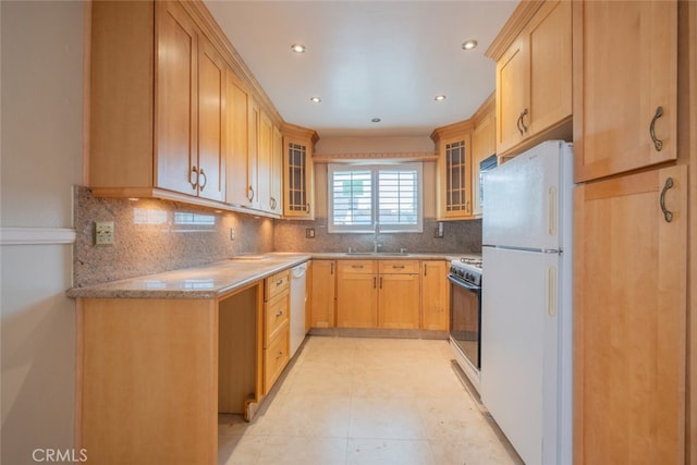 kitchen featuring glass insert cabinets, white appliances, a sink, and light brown cabinetry