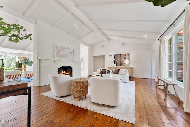 living room featuring a fireplace, a wealth of natural light, hardwood / wood-style floors, and vaulted ceiling with beams