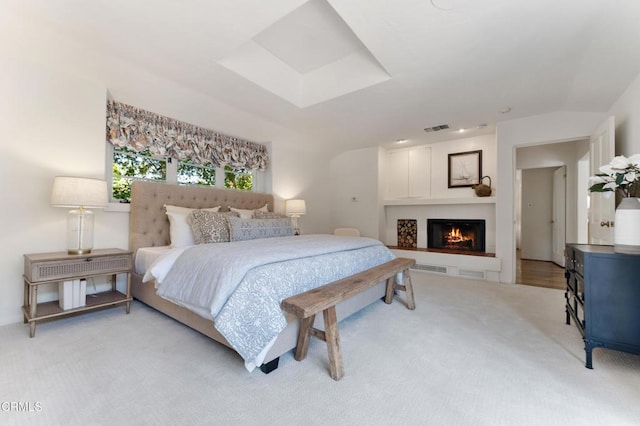 bedroom featuring visible vents, vaulted ceiling, light carpet, and a warm lit fireplace