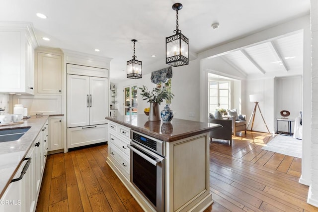 kitchen featuring dark stone counters, paneled fridge, dark wood-style flooring, a notable chandelier, and stainless steel oven