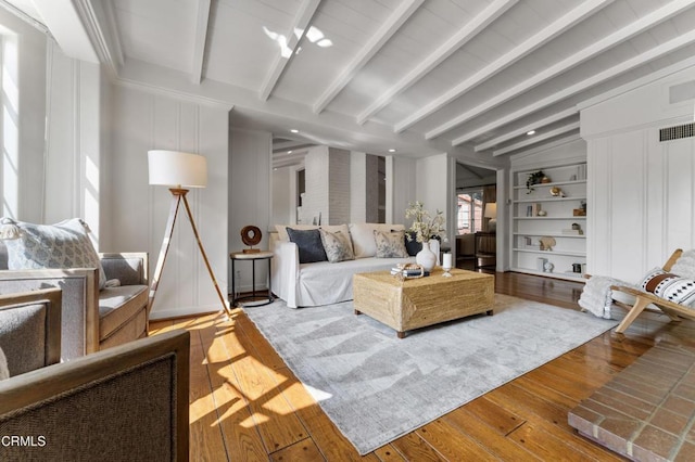living room with visible vents, lofted ceiling with beams, built in features, and wood-type flooring