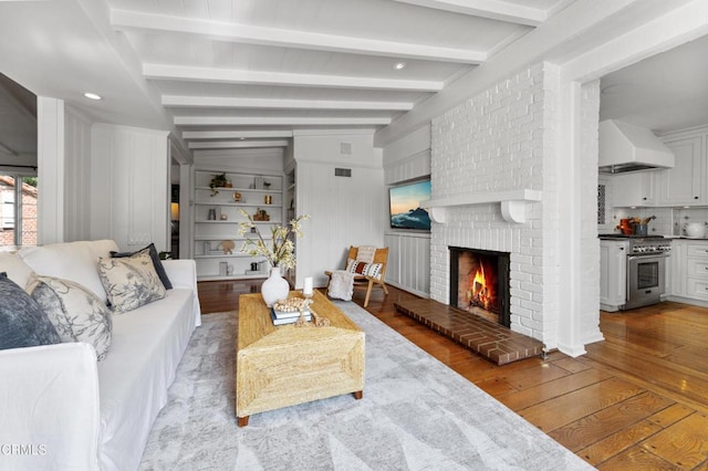 living room featuring a brick fireplace, beam ceiling, and wood-type flooring