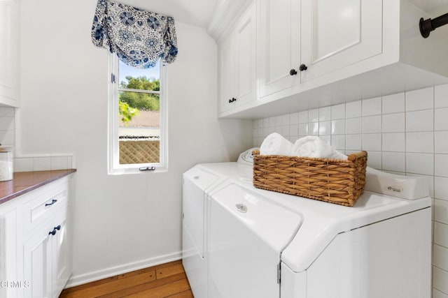 laundry area featuring light wood-style flooring, cabinet space, independent washer and dryer, and baseboards