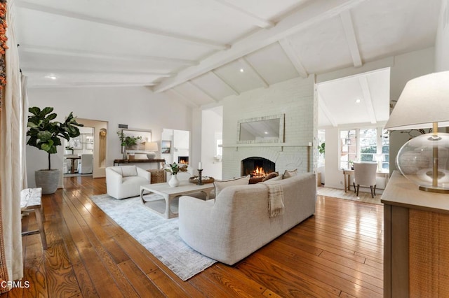 living area with lofted ceiling with beams, wood-type flooring, and a fireplace