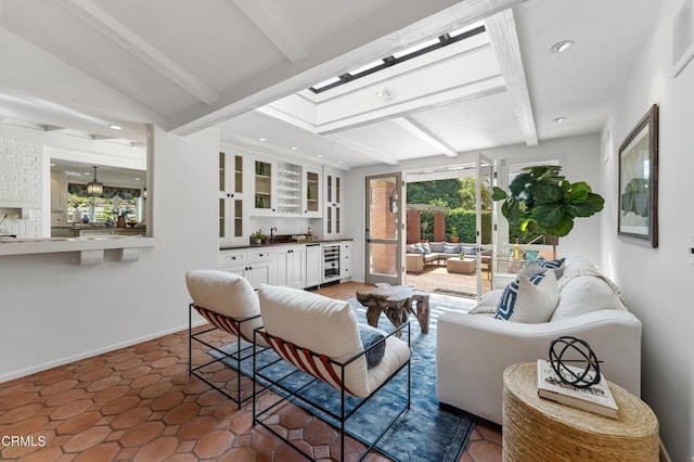 living room featuring beam ceiling, baseboards, bar area, and wine cooler
