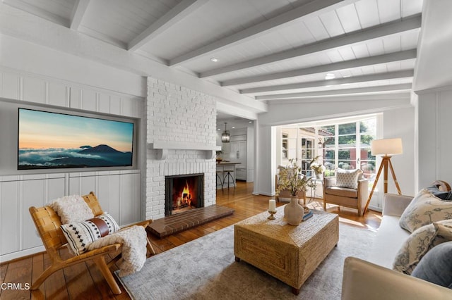 living area featuring a decorative wall, wood-type flooring, and a brick fireplace