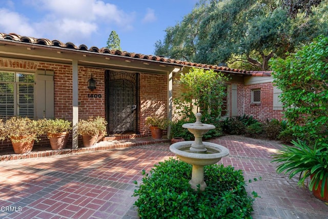 doorway to property featuring a patio and brick siding