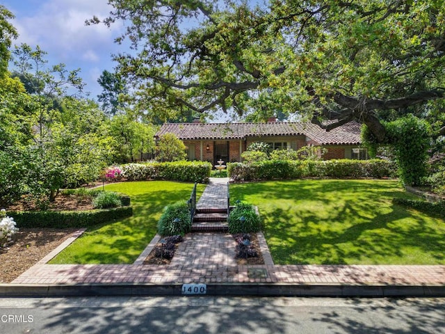 ranch-style home featuring a front lawn and a tiled roof