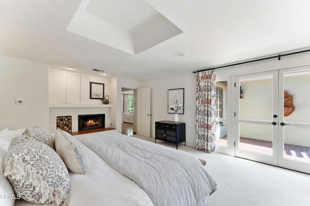 bedroom with access to outside, french doors, carpet, and a warm lit fireplace