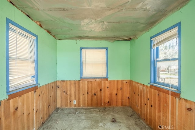 empty room featuring a wainscoted wall and wooden walls