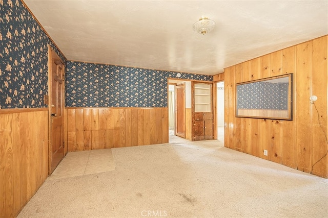 unfurnished room featuring wallpapered walls, carpet, and wainscoting