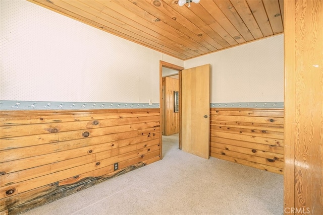 carpeted spare room with wood ceiling