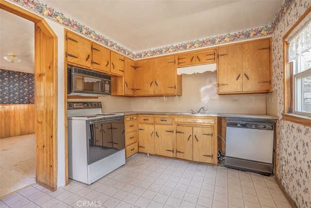 kitchen featuring wallpapered walls, light tile patterned floors, a sink, and white appliances