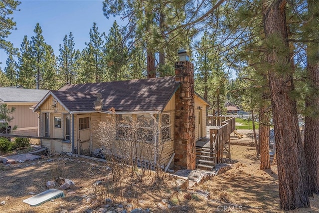 exterior space with a shingled roof and a chimney