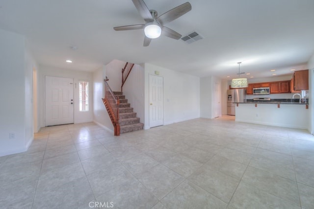 unfurnished living room with stairway, light tile patterned floors, ceiling fan, baseboards, and visible vents