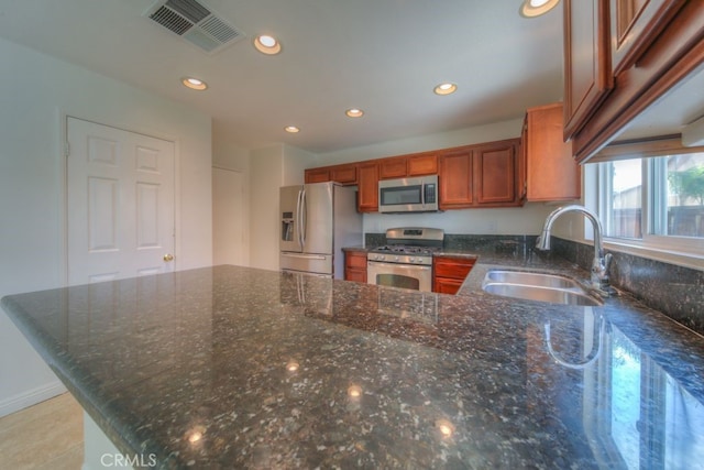 kitchen with dark stone counters, a sink, stainless steel appliances, visible vents, and recessed lighting