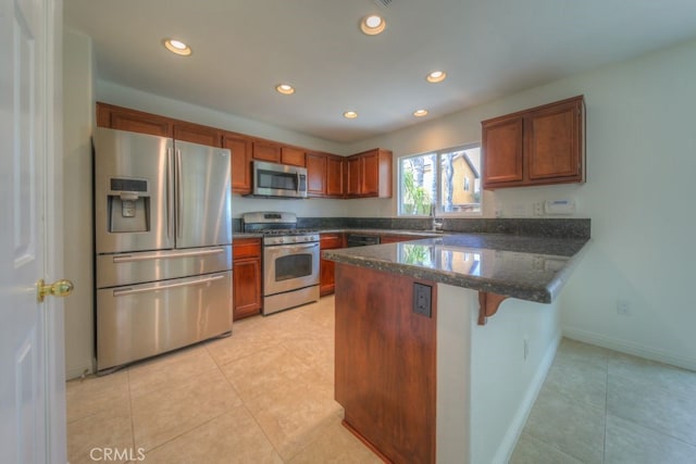 kitchen with brown cabinetry, a peninsula, stainless steel appliances, and recessed lighting