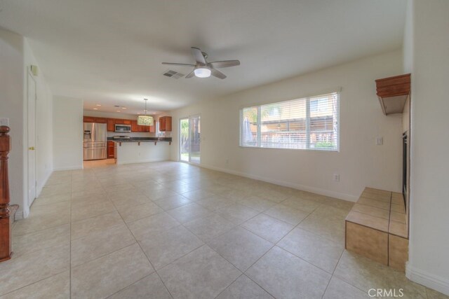 unfurnished living room featuring ceiling fan, baseboards, light tile patterned flooring, and visible vents