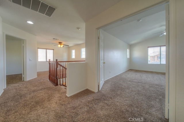hall featuring lofted ceiling, visible vents, carpet, and an upstairs landing
