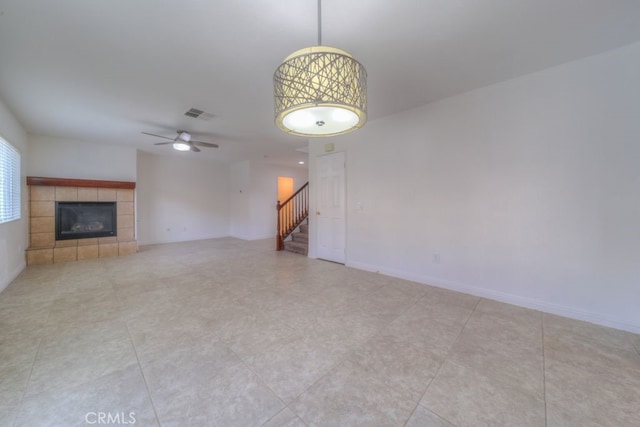 unfurnished living room with a ceiling fan, stairs, visible vents, and a fireplace