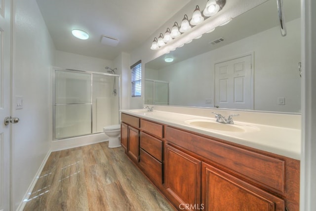 bathroom with a shower stall, wood finished floors, a sink, and visible vents
