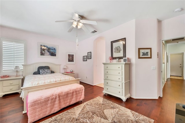 bedroom with visible vents, arched walkways, and dark wood finished floors