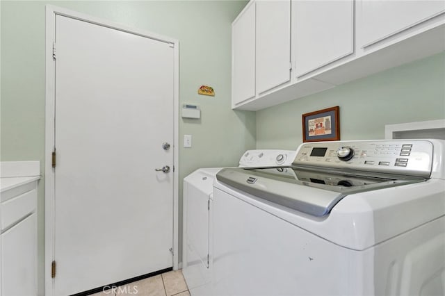 washroom with washing machine and dryer, cabinet space, and light tile patterned flooring