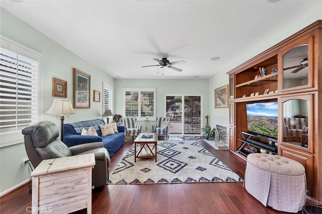 living area with baseboards, a ceiling fan, and wood finished floors