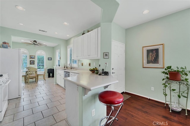 kitchen featuring a breakfast bar area, light countertops, a peninsula, white cabinetry, and visible vents