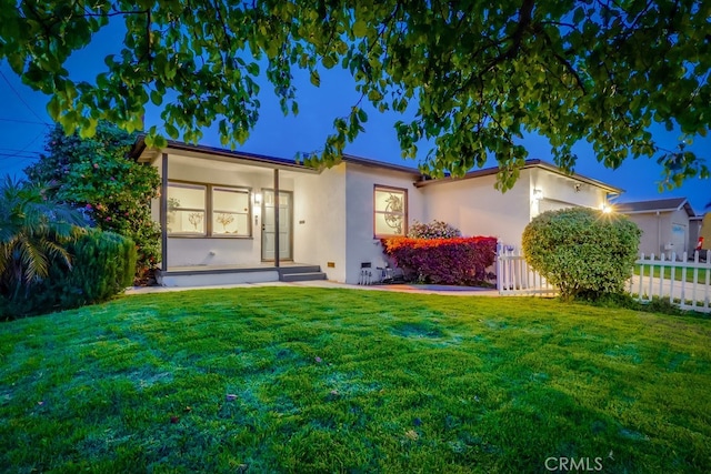 view of front of house featuring a front lawn, stucco siding, and fence