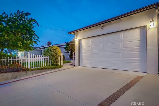 garage with concrete driveway and fence