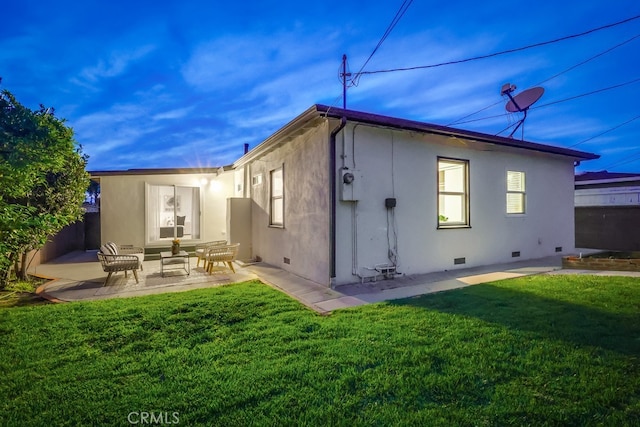 rear view of property with a yard, crawl space, a patio area, and stucco siding