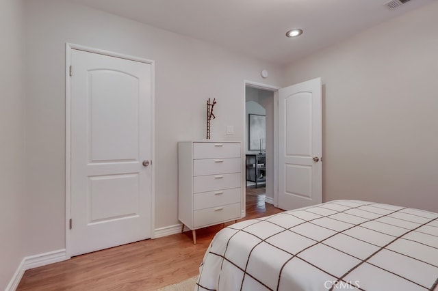 bedroom with baseboards, recessed lighting, and light wood-style flooring