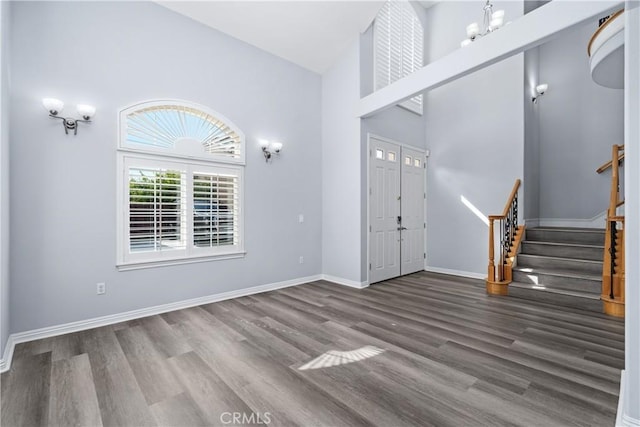 entrance foyer featuring baseboards, high vaulted ceiling, stairs, and wood finished floors