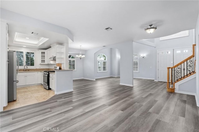 unfurnished living room featuring visible vents, a raised ceiling, and a wealth of natural light