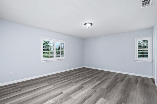 empty room with visible vents, baseboards, and dark wood-type flooring