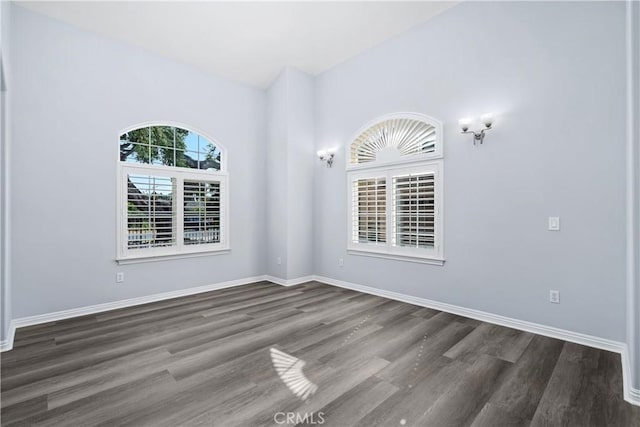 spare room featuring baseboards and wood finished floors