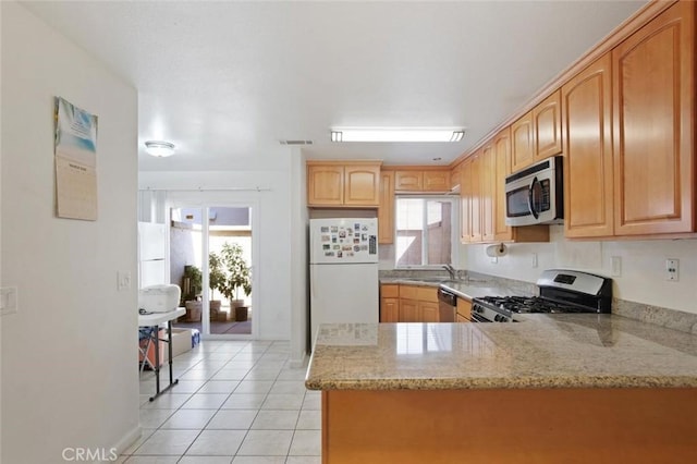 kitchen featuring stainless steel appliances, visible vents, a sink, light stone countertops, and a peninsula