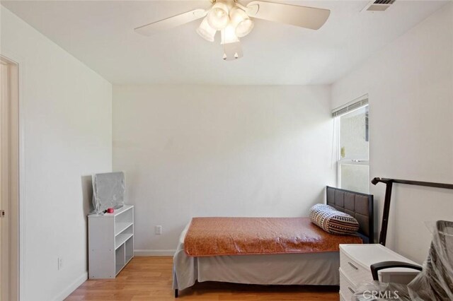 bedroom featuring light wood-type flooring, visible vents, baseboards, and ceiling fan