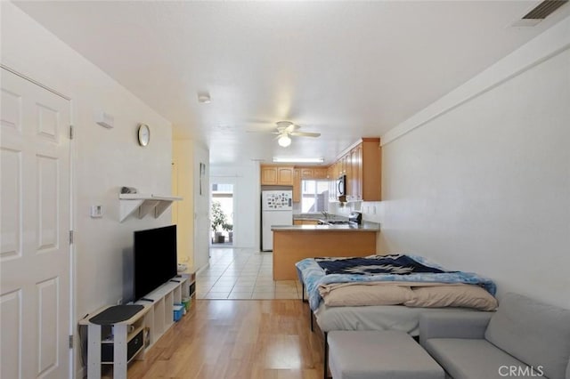 bedroom featuring freestanding refrigerator, light wood-style floors, and visible vents