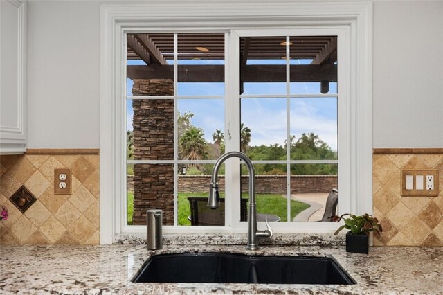 4 Chisholm Trl, Trabuco Canyon, CA 92679 - kitchen view of a sink, white cabinetry, light stone counters, and decorative backsplash