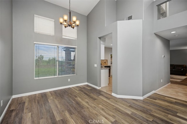 4 Chisholm Trl, Trabuco Canyon, CA 92679 - unfurnished dining area with a towering ceiling, a chandelier, baseboards, and wood finished floors