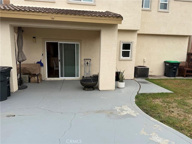 rear view of house with stucco siding, a tile roof, central AC, and a patio