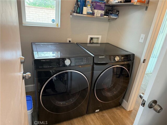 washroom with baseboards, wood finished floors, washer and clothes dryer, and laundry area