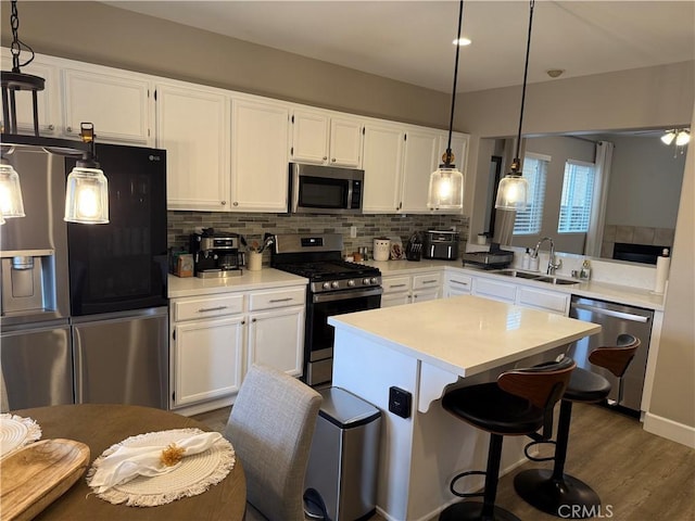kitchen with white cabinets, light countertops, a sink, decorative backsplash, and appliances with stainless steel finishes