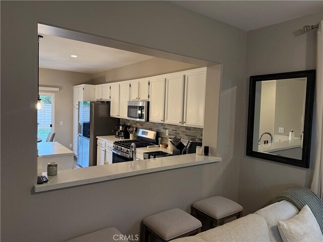 kitchen with decorative backsplash, appliances with stainless steel finishes, white cabinets, and light countertops