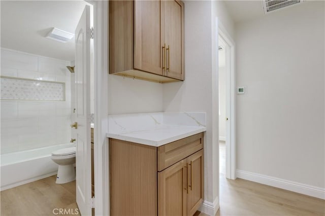 bathroom featuring wood finished floors, visible vents, toilet, and shower / washtub combination