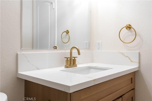 bathroom with a textured wall and vanity
